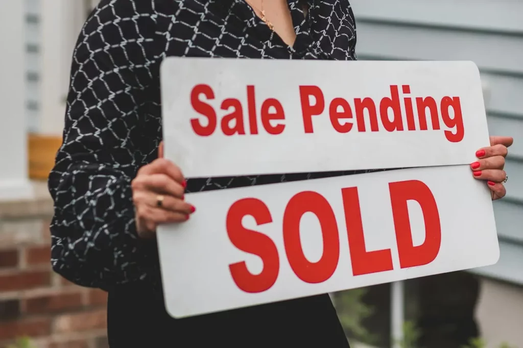 Image of a realtor holding a “Sold” sign